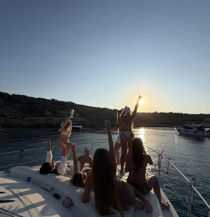 Arms raised to the sunset on the bow