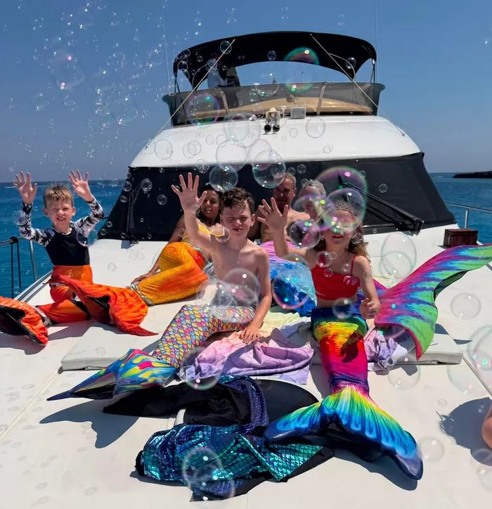Kids in mermaid tails with bubbles on deck