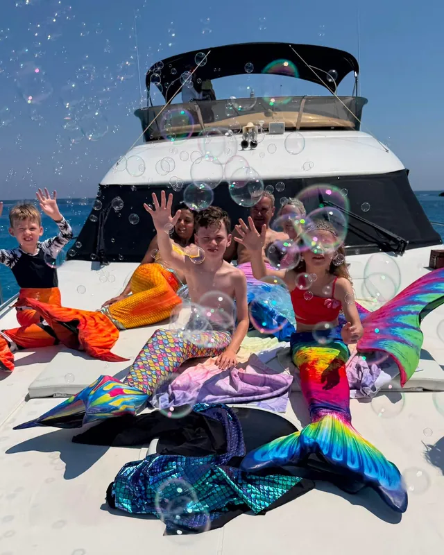 Kids in mermaid tails with bubbles on deck