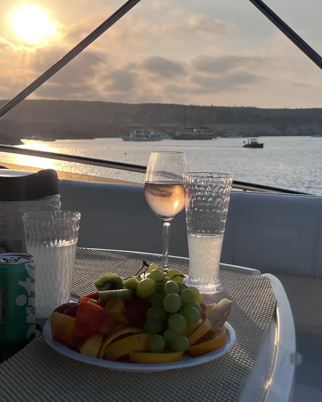 Ein Glas Rosé und eine Obstplatte an Deck bei Sonnenuntergang